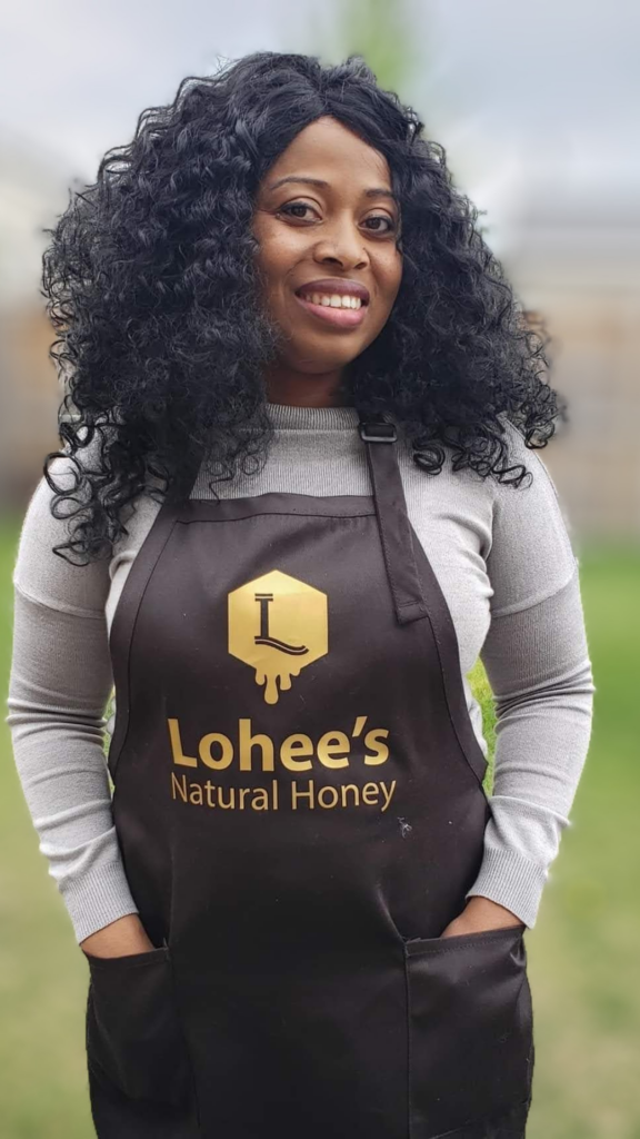 Picture of the founder of Lohees Natural Honey wearing a a beautiful smile and a customized apron over her dress.